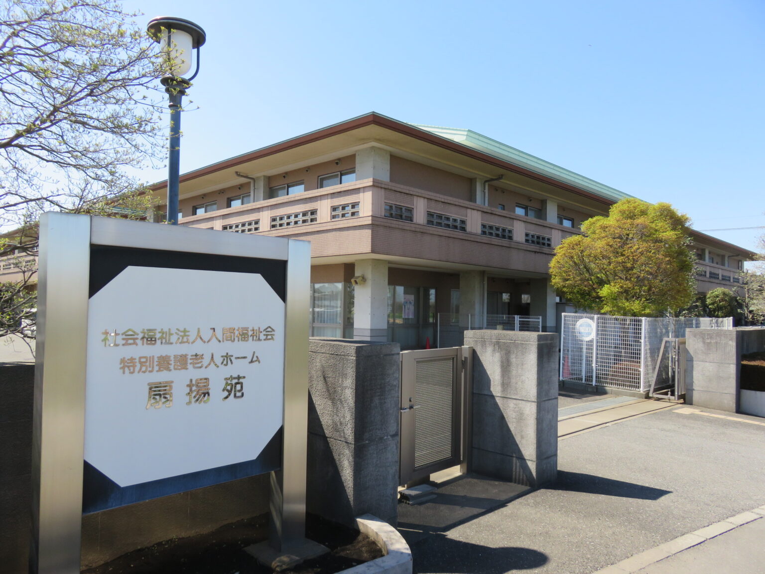介護施設の建物外観。モダンな平屋建て構造で、入口にロゴサインが設置されている。